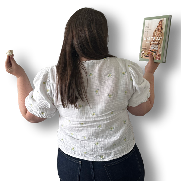 Picture of the back of Emily holding a cookbook and a sea shell