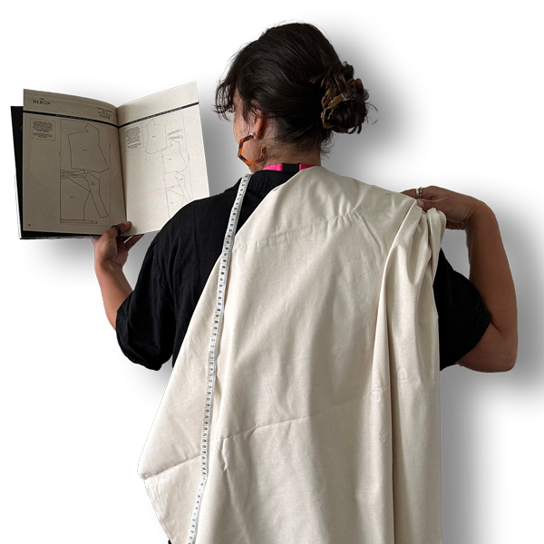 Picture of the back of Lizzie holding a sewing book, some fabric, and a measuring tape